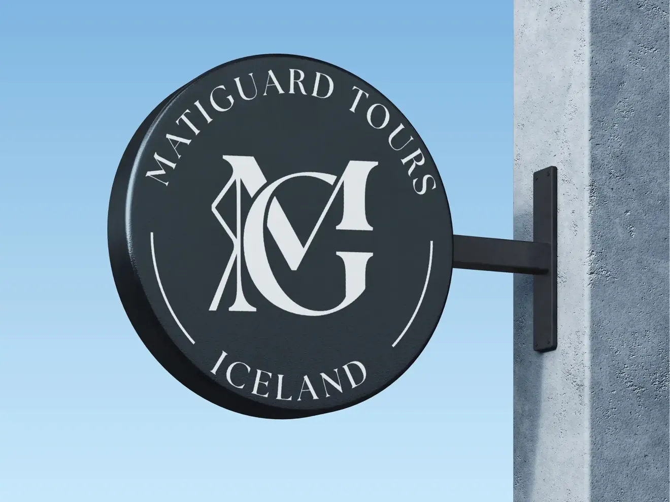 Okrągły szyld marki Matiguard Tours Iceland z monogramem MG, zamocowany na metalowym wsporniku przy jasnej elewacji budynku.
